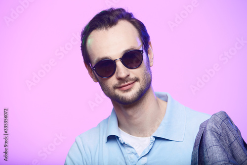 Studio shot of handsome man wearing sunglasses over pink background.