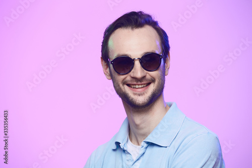 Studio shot of handsome man wearing sunglasses over pink background.