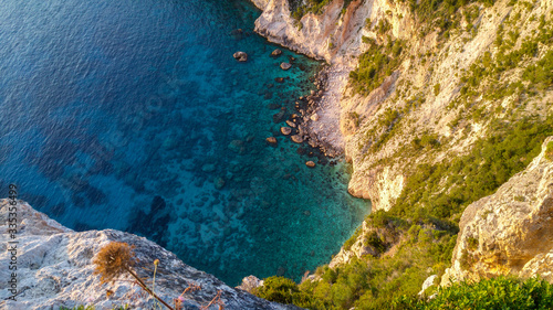Blue and turqoise water in a bay, from top view, rocks and green shrubs in the deep