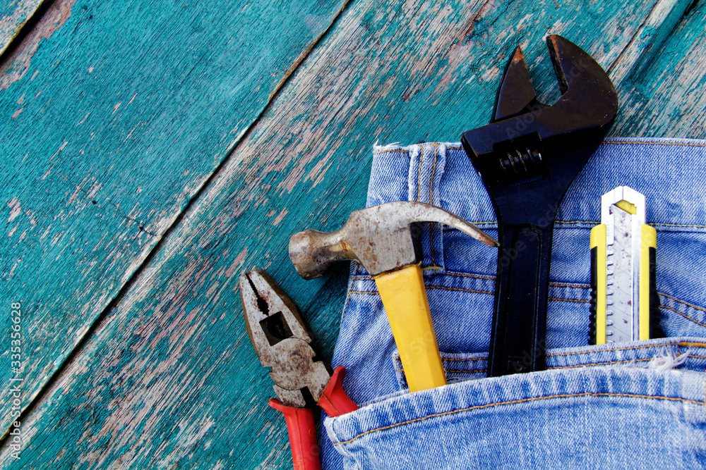 Hand tools on the blue jeans over blue wooden background. Happy labor day