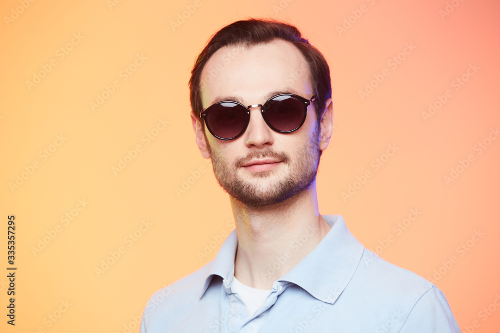 Studio shot of handsome man wearing sunglasses over orange background. Studio shot of handsome man wearing sunglasses over orange background.