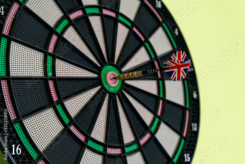 Close-up of a dart arrow with the English flag in the center of the dart board to represent that the company or the country achieved the company's objective. Objective and goal as a concept.