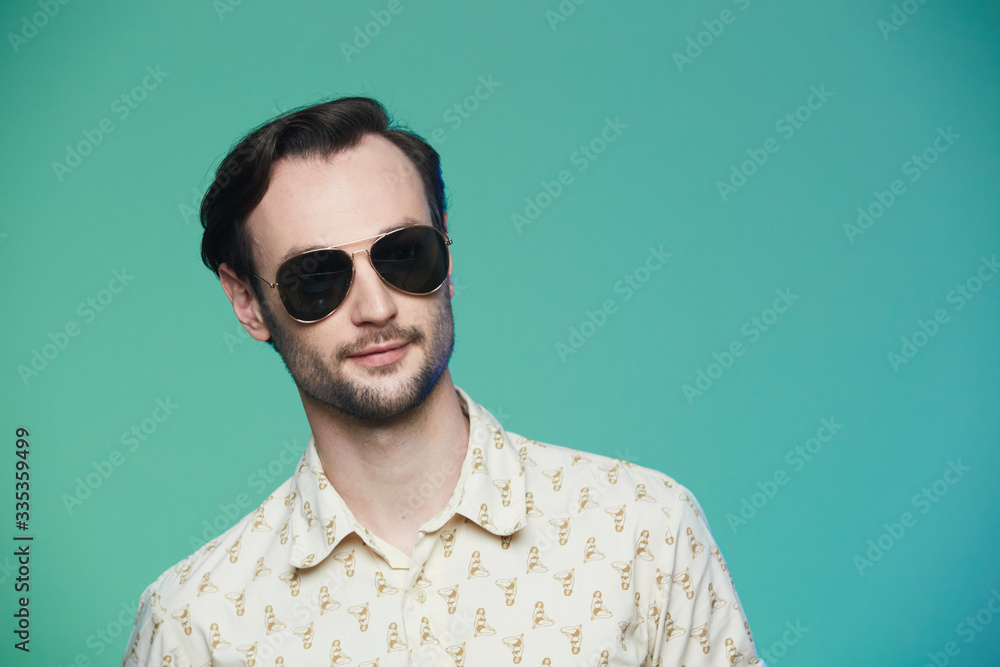 Studio shot of handsome man wearing sunglasses over green background. Studio shot of handsome man wearing sunglasses over green background.
