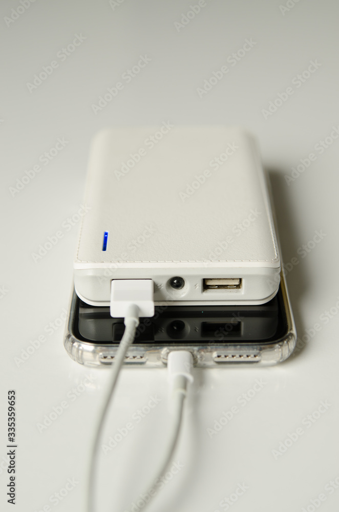 Smartphone charging with power bank on white background Smartphone charging with power bank on white background