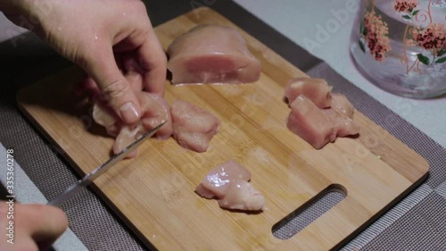 man puts a piece of raw chicken meat on a cutting board, cooking at home