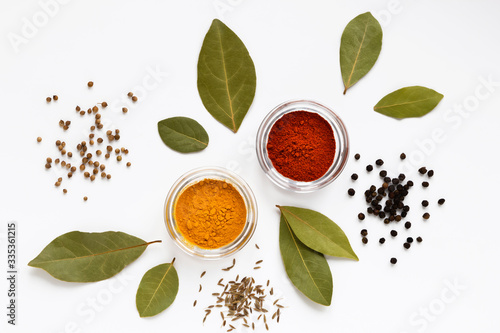 set of assorty colorful spices and herbs in bowls on white background, flat lay, top view photo