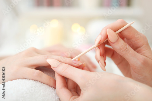 Closeup shot of a woman in a nail salon getting a manicure by a cosmetologist with a nail file. Woman gets a manicure of nails. Beautician puts nails on the client. 