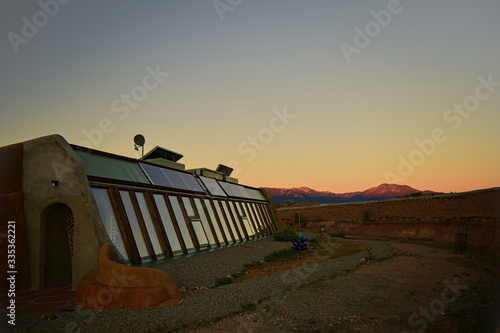 Front side view of self sustaining eco-friendly Earth ship home at sunset with mountains in background of landscape in Toas, New Mexico. photo