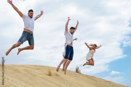A group of friends enjoying the summer and jumping in the sand dunes of the beach.