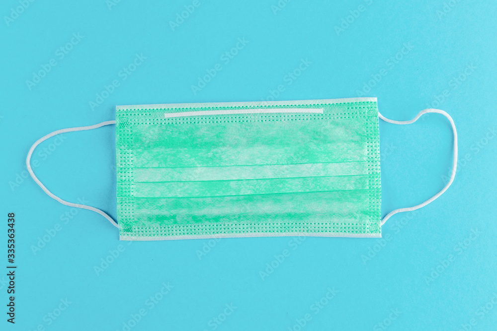 green medical mask on blue color background, concept of protection against flu, viruses and other diseases green medical mask on blue color background, concept of protection against flu, viruses and other diseases