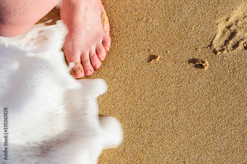 Young woman's foot on wet sand with moving wave photo