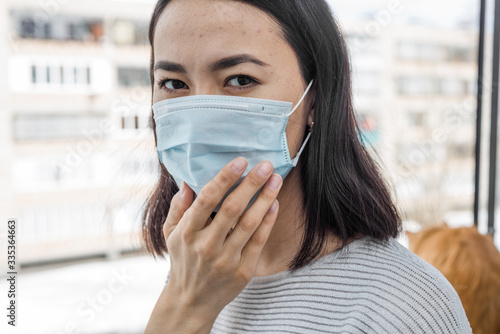 Portrait of a young Asian woman in a medical mask close-up on the street. protection from coronavirus and flu. in self-isolation and distancing due to the coronovirus pandemic
