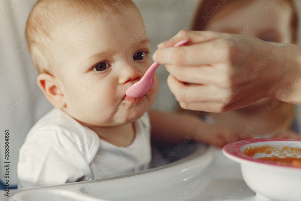Baby eating. Mother feeds the baby. Little child in a kid's chair. Baby eating. Mother feeds the baby. Little child in a kid's chair.