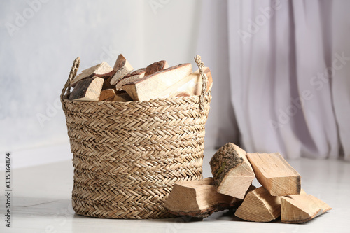 Valokuva Wicker basket with cut firewood on white floor indoors