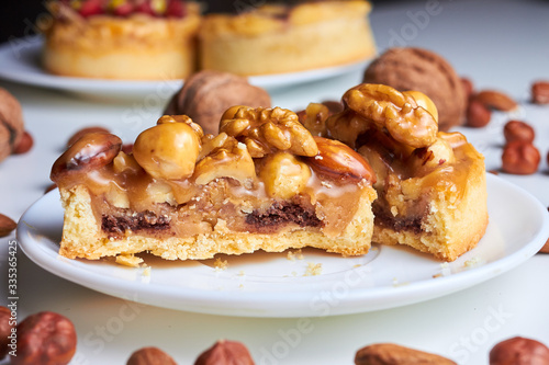 Сut mini tart cupcake mini tart cupcake with walnuts, almonds and hazelnuts on plate. Close up.