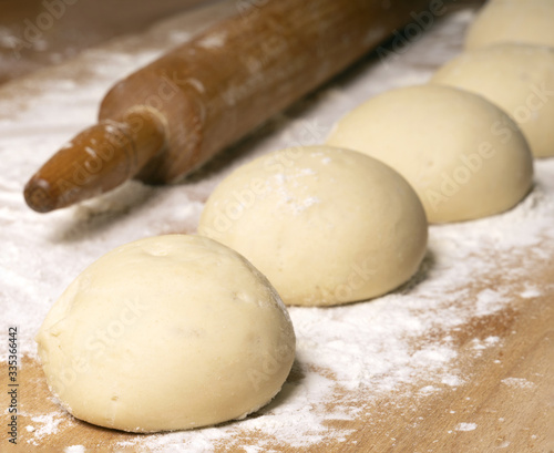Rolling pin and balls of dough on a wooden board, soft selective focus