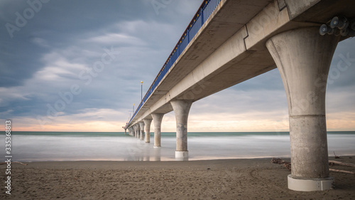 Massive concrete pier leading to horizon surrounded by ocean. Long exposure shot made in New Brighton Beach in Christchurch, New Zealand © Peter Kolejak