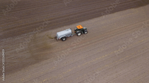 Traktor mit Gülletonne bringt Gülle auf Acker aus, Landwirtschaft