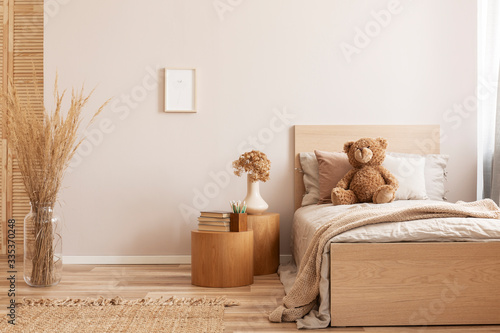 Bright and natural hotel room interior with single bed and wooden nightstand with flowers