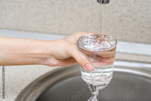 consumption of fresh water. pour water into a glass from the tap. water supply. drinking water filtration
