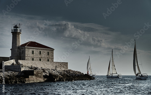 Wallpaper Mural Sailboats compete in a sailing regatta at sunset, sailing race, reflection of sails on water, multi-colored spinnaker, boat number aft boats, big white clouds, the island with a lighthouse Torontodigital.ca