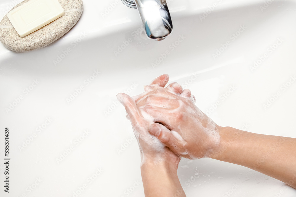 Fototapeta premium A Hands with soap are washed under the tap with water. Clean from infection and dirt and virus. At home or in the hospital ablution office.