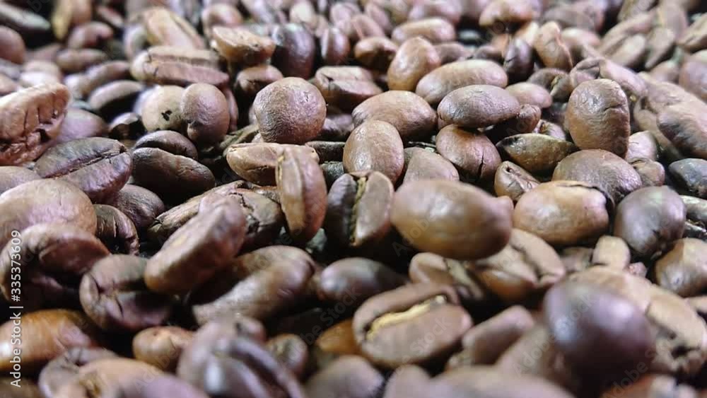 Close-up view of roasted coffee beans are falling and spinning in slow motion Close-up view of roasted coffee beans are falling and spinning in slow motion