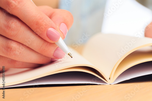 female hands write in a notebook . Office place . Close up view  - Image