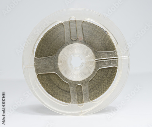 A beautiful clean vintage 8mm movie film reel with movie film on the spool. Vintage americana movie film reel isolated on a white studio background. Home movies for projection, cinematic entertainment