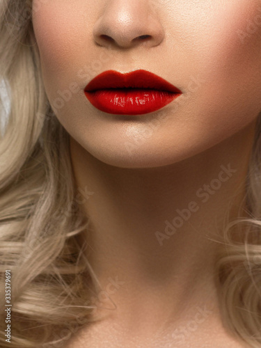 Close-up of woman s lips with fashion natural beige lipstick makeup. Macro sexy red lipgloss make-up . Gentle pure skin and wavy blonde hair. Cosmetology  Spa  increase in lips