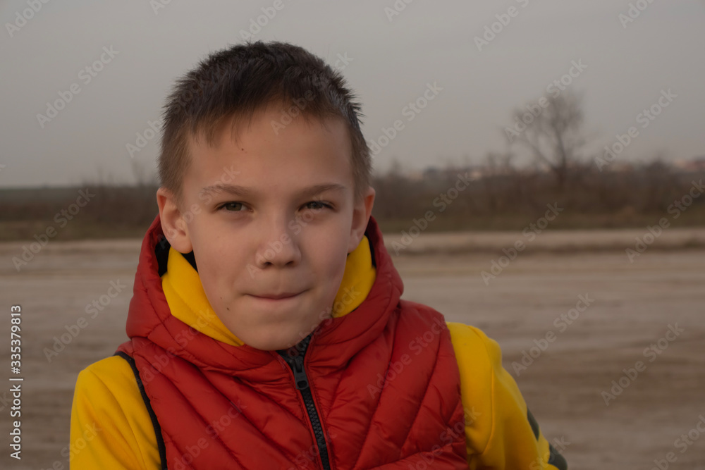 A boy of 10 years in an orange vest on an empty beach during quarantine. A boy of 10 years in an orange vest on an empty beach during quarantine.