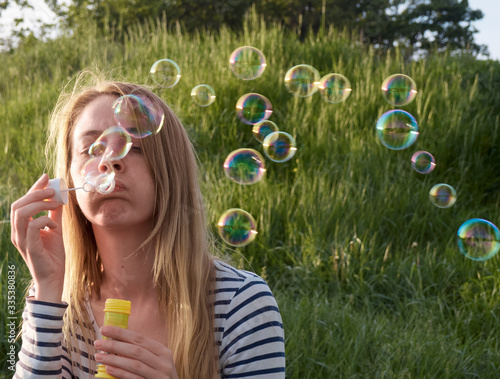 Girl inflates bubbles at sunset.