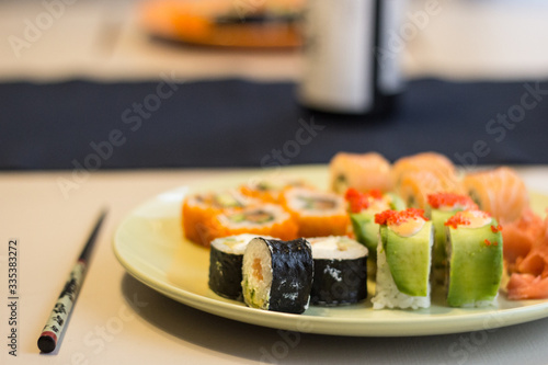 Sushi maki close-up on a green plate in warm colors with a blurred background.