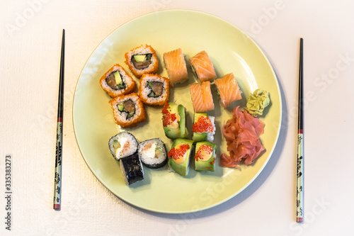 Green plate with a set of sushi maki in warm colors.