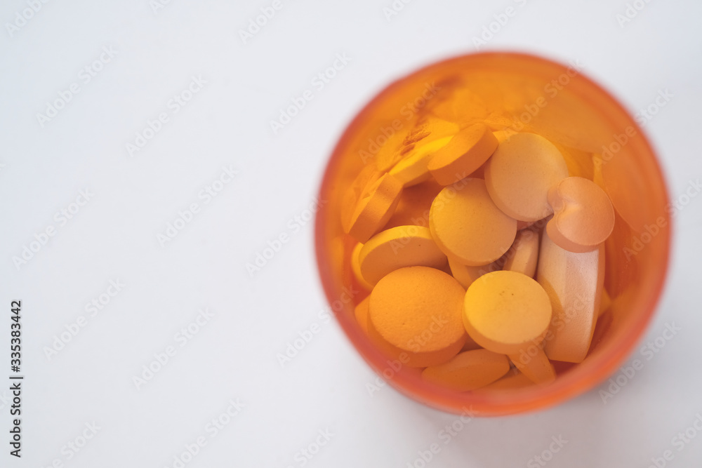 white pills in a container on orange background white pills in a container on orange background