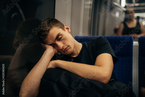 Passenger sitting in the seat and sleeping inside a train/bus while traveling.Tired exhausted looking young man getting away with train ride.Going home from work.Bored person during commute time.Nap