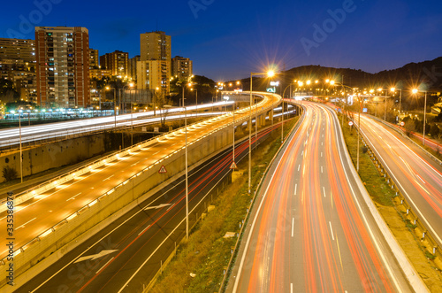 Paisaje urbano de la entrada de la autopista a Barcelona de noche. con los rastros de las luces de los coches 