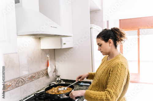 Pregnant woman cooking with serious expression in a kitchen