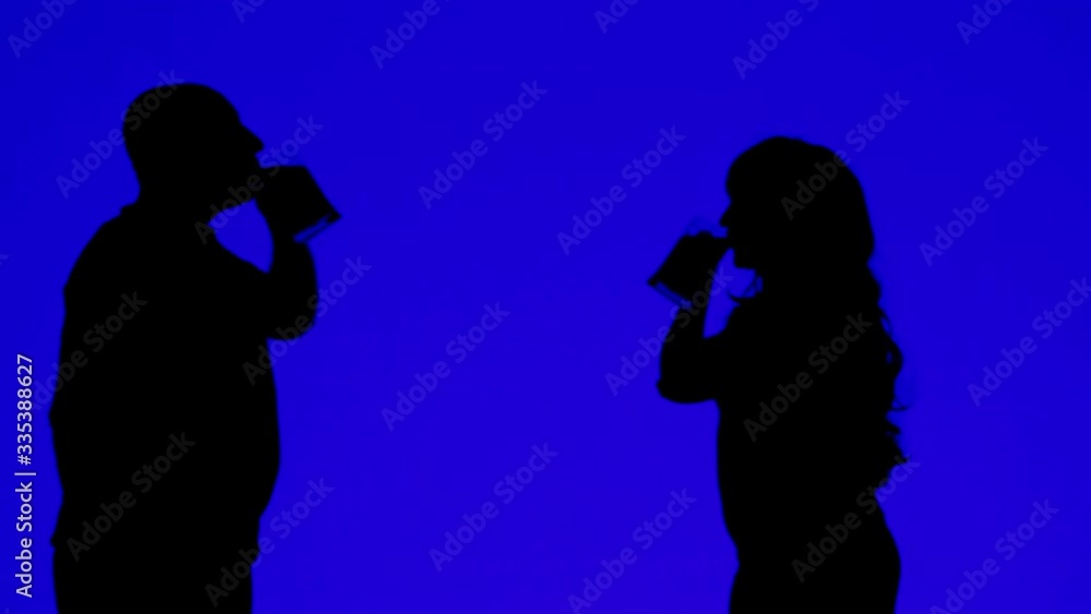 Silhouette of a woman and a man drinking beer from mugs on a blue background Silhouette of a woman and a man drinking beer from mugs on a blue background