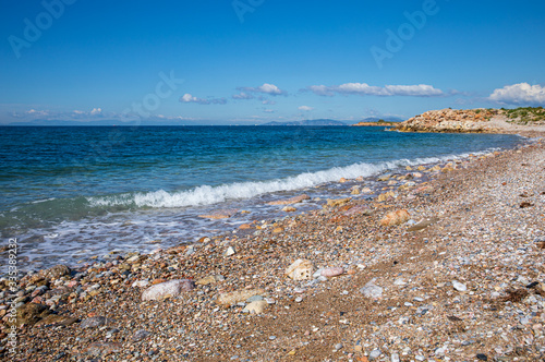 Fototapeta Naklejka Na Ścianę i Meble -  Beautiful seascape with calm sea, pebbles beach, blue sky of suburb in South Athens located in the Athens Riviera, Greece.