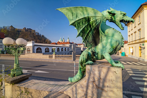 Dragon statue on Dragon bridge and Ljubljana castle and Saint Nicholas Cathedral in the background, Ljubljana, Slovenia photo