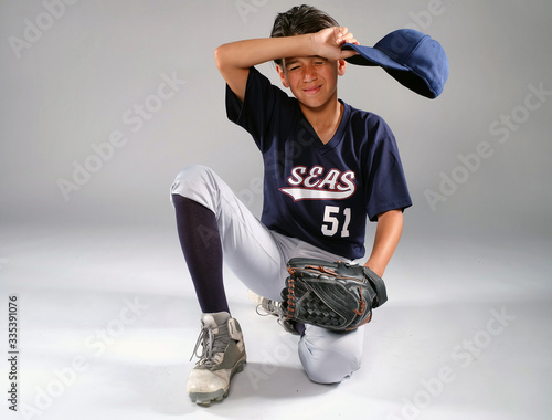 Photography Exhausted young baseball player wipes his brow with his cap