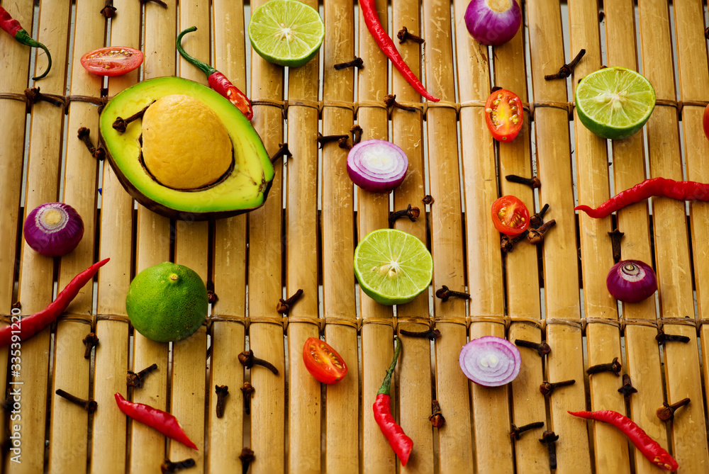 Culinary background. Top view of pattern of fresh vegetables and spices on the bamboo wooden background. Ingredients for sauce guacamole.