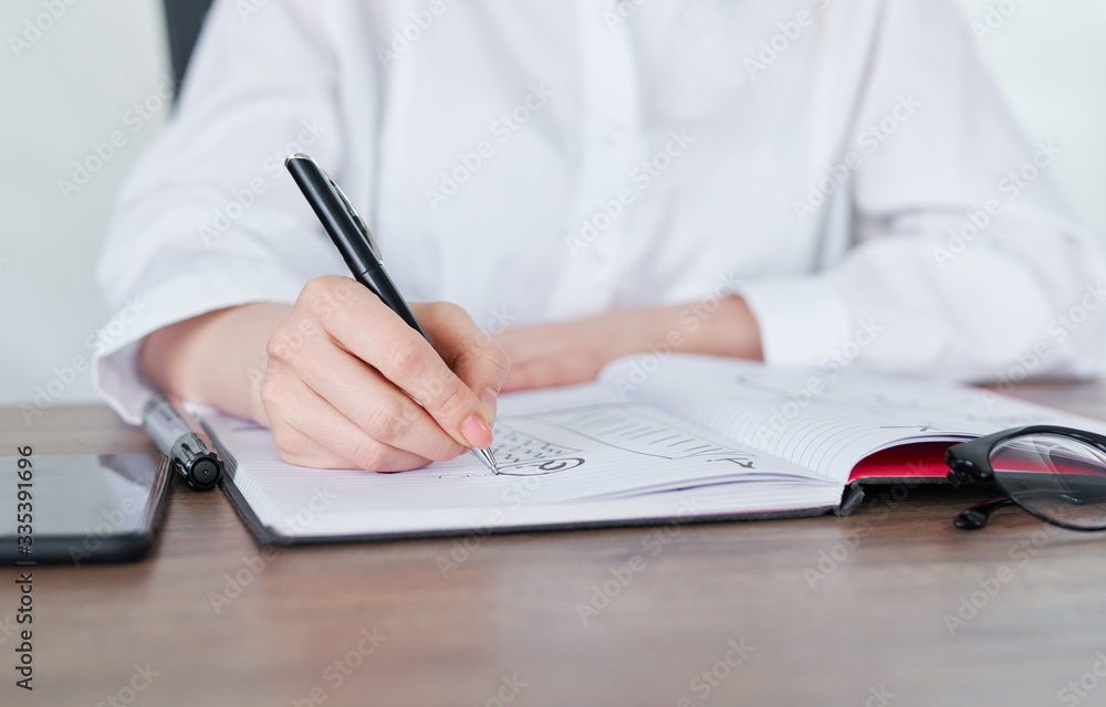 Business Woman Writing with pen in notepad Business Woman Writing with pen in notepad