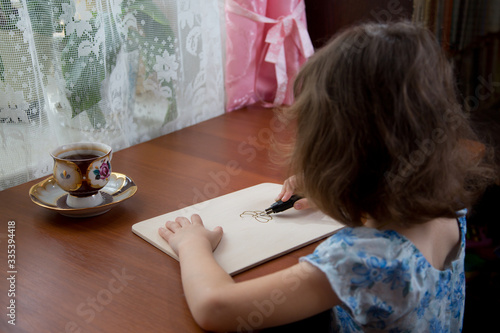 girl draws a picture with a pyrograph on a wooden board photo