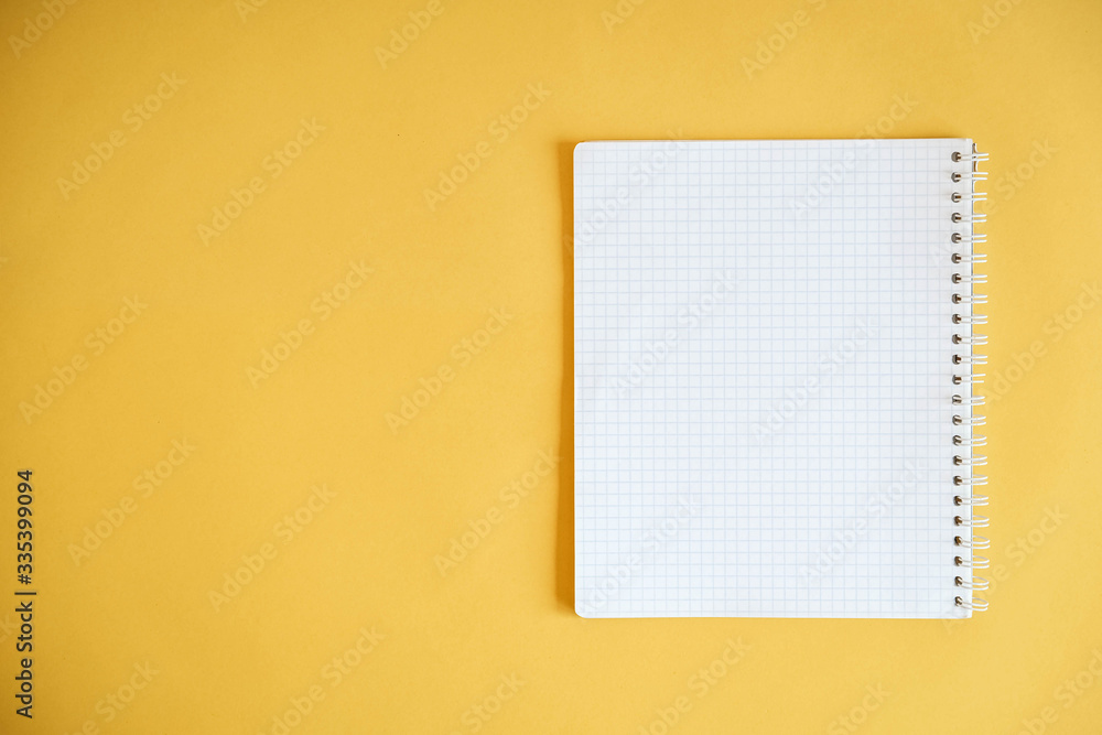 Blank notebook for writing on yellow background. Top view. Copy, empty space for text Blank notebook for writing on yellow background. Top view. Copy, empty space for text