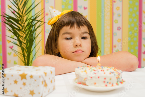 holiday, birthday of a girl, a child of 7 years old on the table a cake with a candle and a gift, the theme of the holiday without friends in quarantine