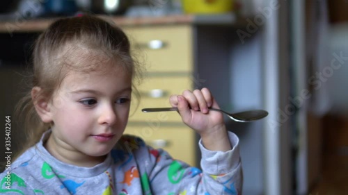 Little girl refuses to eat. Child holding spoon and looking not famished.