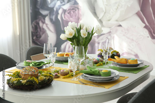 Festive Easter table setting with beautiful white tulips and eggs indoors