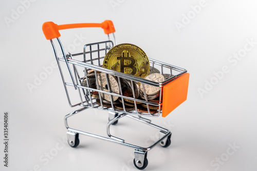 Bitcoins, euro and other currencies filling up shopping trolley, isolated on white background. To illustrate the financial and economic fluctuations and challenges during covid 19 crisis. photo